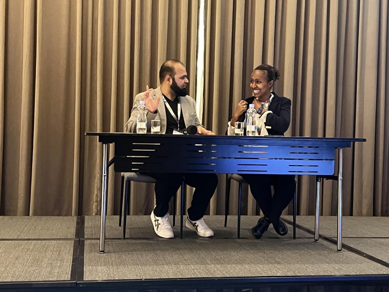 Two participants seated on stage during an AFROC panel session.